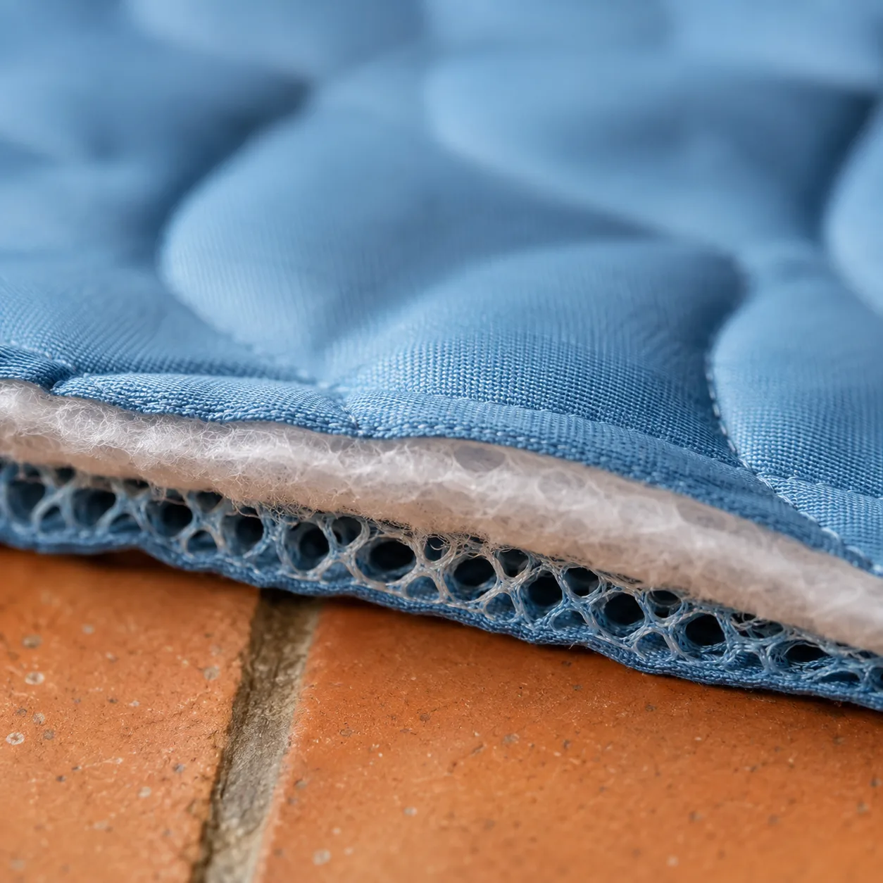 Gros plan sur le textile du tapis rafraîchissant Frimouf : la soie glacée de la face supérieure et la maille respirante du dessous